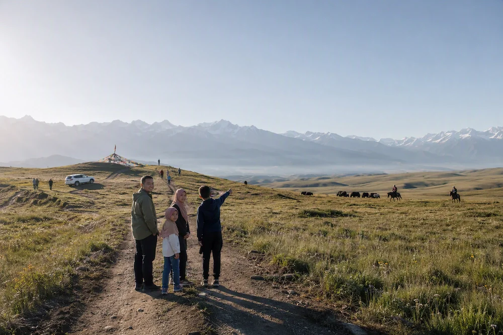 Family of four on a grassland trail looking toward snow-capped mountains in Qilian